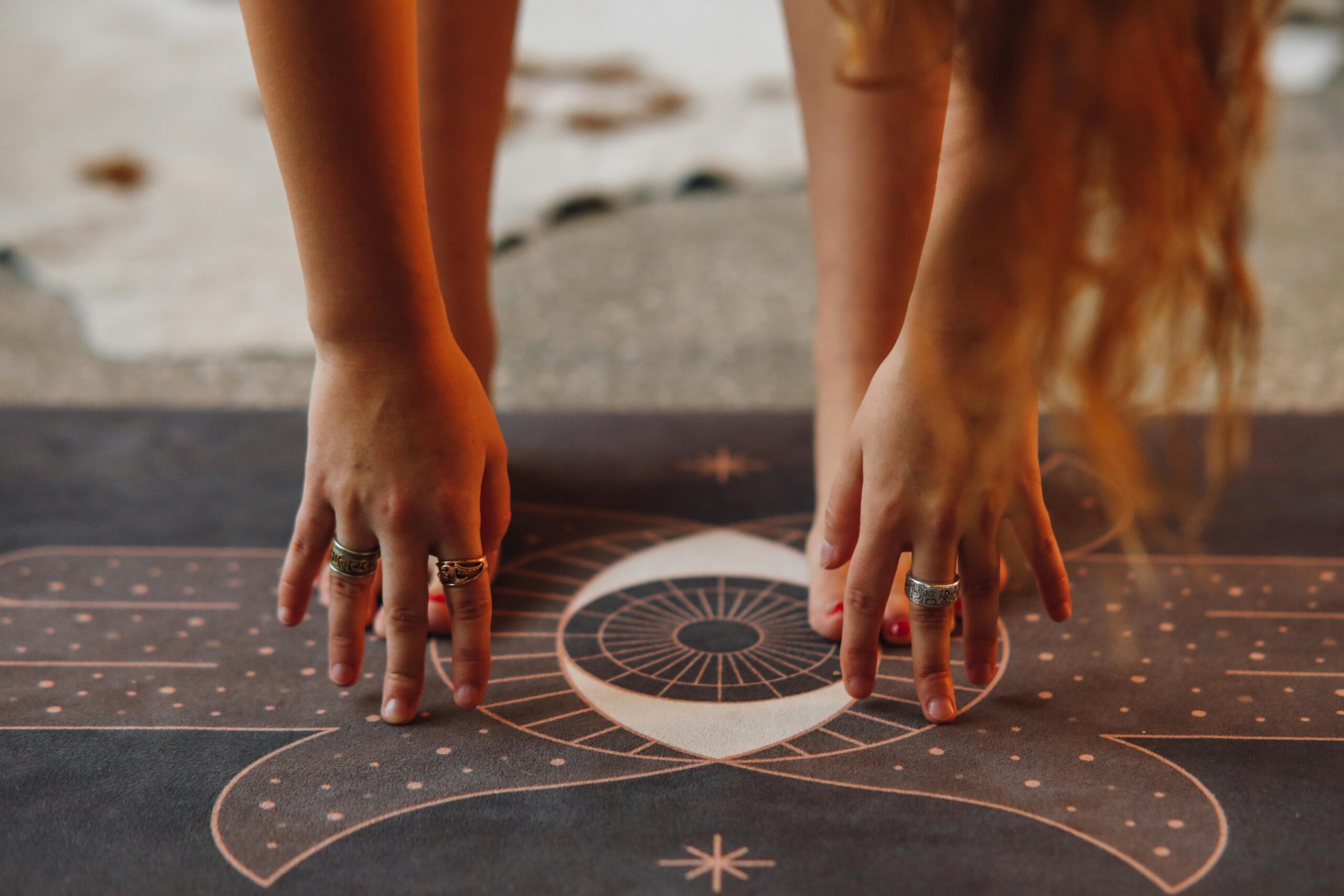 Detailed view of hands with rings in yoga pose on a decorative mat.