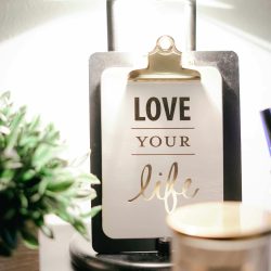 A warmly lit desk setup featuring a lamp, inspirational clipboard, and decor for a cozy ambiance.